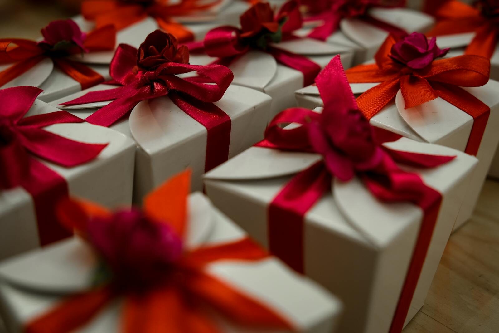 Close-up of white gift boxes adorned with vibrant red and orange ribbons, ideal for celebrations.